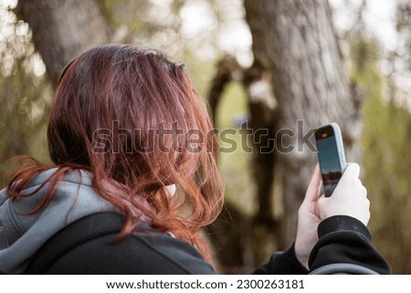 A red hair woman takes a photograph on the phone