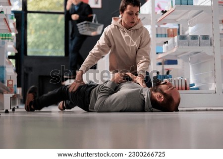 Woman helping man having foaming at mouth and convulsion during epileptic seizure in pharmacy retail store. Drugstore customer holding person having epilepsy attack, providing first aid Royalty-Free Stock Photo #2300266725