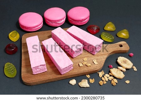 Pink macarons and pink marshmallows lie on a dark background. Sweets. Marmalade. Delicious dessert