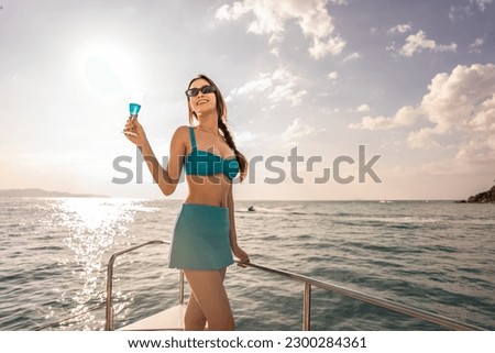 Caucasian woman in bikini drink champagne while having party in yacht. Attractive beautiful female tourist hanging out celebrate holiday vacation trip while catamaran boat sailing during summer sunset