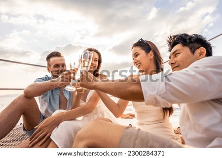 Group of diverse friends drink champagne while having a party in yacht. Attractive young men and women hanging out, celebrating holiday vacation trip while catamaran boat sailing during summer sunset. Royalty-Free Stock Photo #2300284371