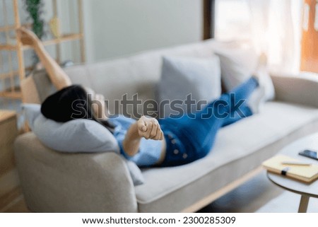 Home lifestyle woman relaxing sleeping on sofa  patio living room. Happy lady lying down on comfortable pillows taking a nap for wellness and health. Tropical vacation