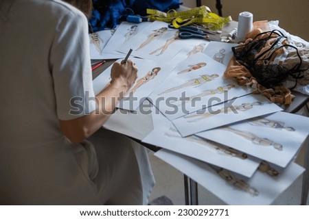 Faceless woman draws sketches of swimwear. Close-up of the hands of a fashion designer.