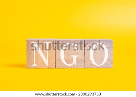 A technical term of NGO on wooden cubes on yellow background, Non-governmental Organization, Nobody
