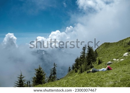 a women lay down on the ground, background with high mountain and beautiful cloud.This photo took at Switzerland.