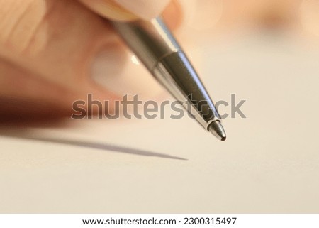 Close-up of woman hand holding ballpoint pen and signing documents. Conclusion of contracts and transactions concept