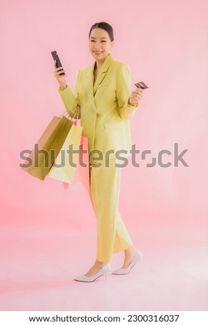 Portrait beautiful young asian business woman with shopping bag on color isolated background