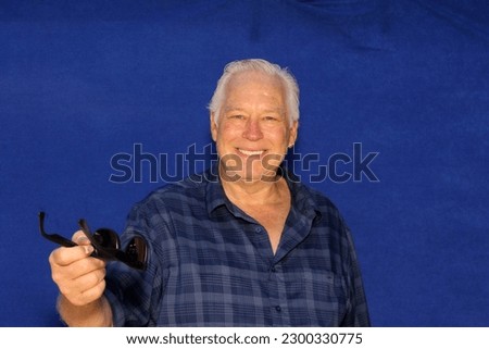 Photo Booth. Photo Booth Pictures. A man smiles and poses while in a Photo Booth with a Blue Velvet Background. A handsome man laughs, smiles, and poses with crazy props while in a Photo Booth. 