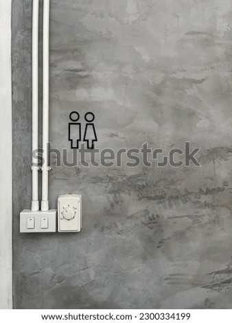 Male and female toilet sign on modern cement wall, cement wall and power outlet