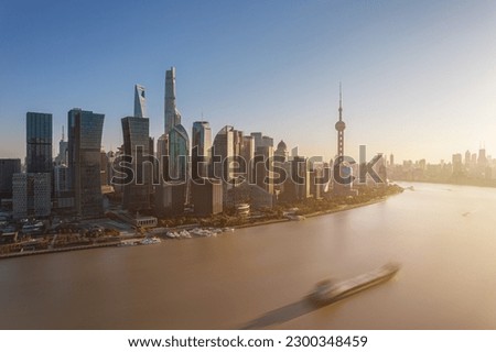 shanghai skyline in the day, showing the Huangpu river with passing cargo ships, financial district and cloudy sky background