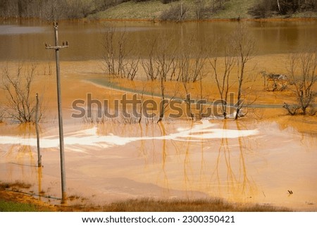 A lake contaminated with toxic waste in the western mountains of Romania. Nature pollution from copper mine. Ecological catastrophe or Environmental disaster. Royalty-Free Stock Photo #2300350421