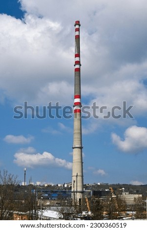 Industrial area with tall chimney with cloudy sky in background