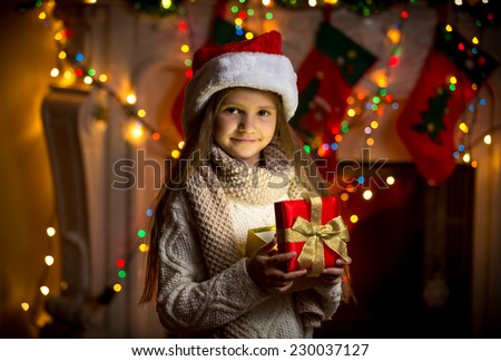 Closeup portrait of smiling girl opening sparkling gift box at Christmas