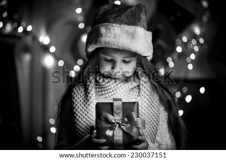 Black and white portrait of smiling girl opening Christmas present box