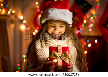 Portrait of little girl looking at open box with Christmas present