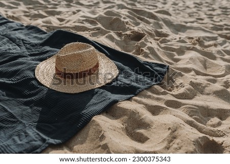 Straw hat, beach towel on beach sand. Minimal fashion vogue background. Flat lay, top view