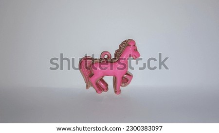 3D pink and gold colored horse decoration on a white background.