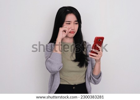 Asian young woman crying sad when looking to her mobile phone Royalty-Free Stock Photo #2300383281