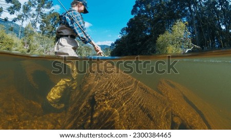 Woman angler on the river. Woman walks in the water in waders. Woman fishing on the river Royalty-Free Stock Photo #2300384465