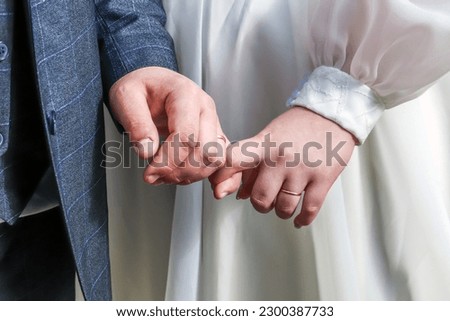 Friendship and connections. Newlyweds hold hands. Plump hands of the bride and groom with wedding rings and a bouquet. Close-up