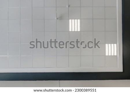 cassette stretched or suspended ceiling with square halogen spots lamps and drywall construction in empty room in house or office with column. Looking up view