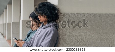 teenagers on the wall using mobile phone Royalty-Free Stock Photo #2300389853