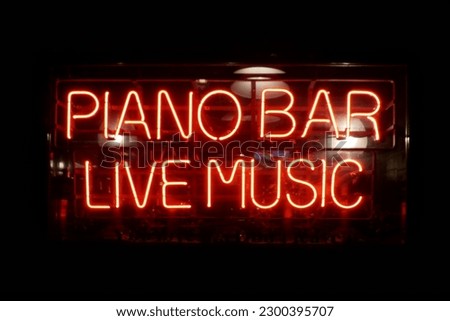 Close-up on a neon light shaped into the short phrase "Piano Bar, Live Music".