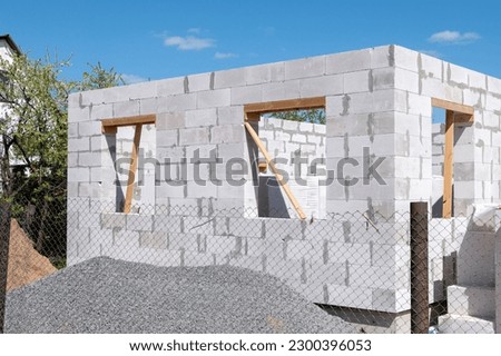 Construction of a house from gas silicate white blocks. A mountain of gravel and sand near an unworthy house. Building a house in the countryside Royalty-Free Stock Photo #2300396053