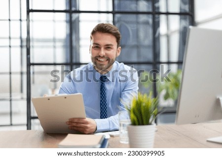 Young man is working with papers while sitting in the office. Successful entrepreneur is studying documents with attentive and concentrated look.