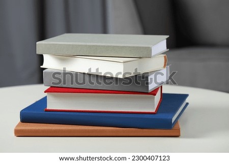 Stack of hardcover books on white table, closeup