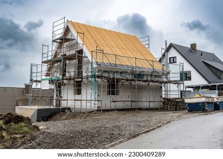 Construction of new houses in the village. A building under construction and scaffolding against the sky Royalty-Free Stock Photo #2300409289