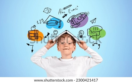 School kid looking at the camera with book on head, educational icons doodle sketch with books and rocket flying on blue background. Concept of learning, knowledge and studies Royalty-Free Stock Photo #2300421417