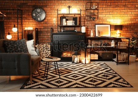 Stylish living room with beautiful fireplace, armchair and different decor at night. Interior design
