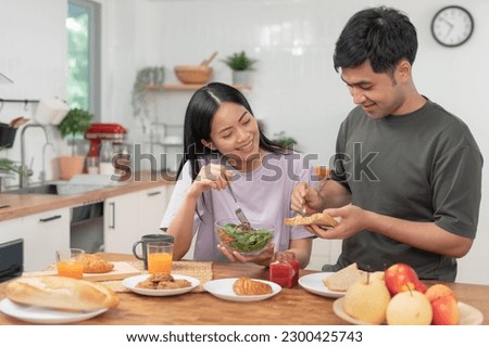 Asian couples are enjoying new home and eating breakfast together. husband and wife after marriage. Happiness and smiles and laughter in warm family. cuddling, warm hugs, Happy family and happy day.