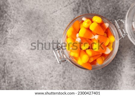 Halloween candy corn with pumpkin flavor and dragees on a black background. Classic sweet Halloween treats. Halloween holiday concept and Jack lantern.Place for text. Place to copy.