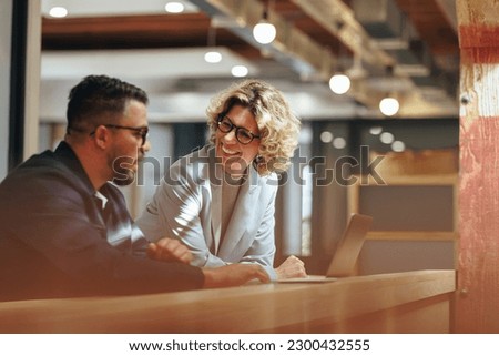 Successful business people working together in a coworking office. Two business professionals working on a tech project. Business colleagues talking to each other. Royalty-Free Stock Photo #2300432555