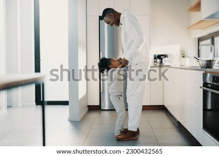 Man playing a game with his young daughter in the morning at home. Father and daughter having fun together in the kitchen.