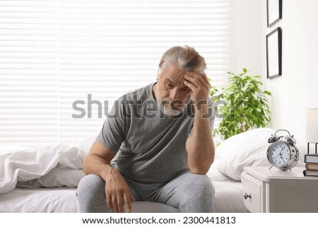 Sleepy senior man in bed at home Royalty-Free Stock Photo #2300441813