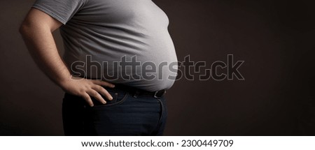Overweight man's belly,fat man has excess fat, he is dieting and losing weight.unhealthy,medical health concept with copy space space for text Royalty-Free Stock Photo #2300449709