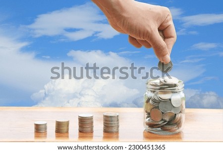 Hand putting coin in glass bottles with plants glowing, Saving money , investment and economize concepts  Royalty-Free Stock Photo #2300451365