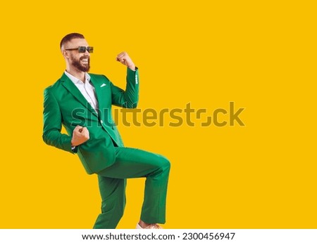 Yes, awesome, cool. Side view of happy smiling overjoyed handsome man wearing trendy green suit and spectacles dancing isolated on yellow copy space background, celebrating success and having fun