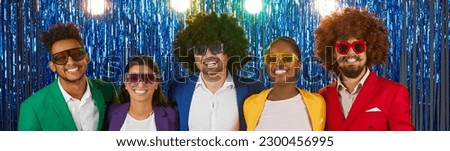 Portrait of five funny male and female retro disco party people on shiny foil background. Headshot of multiracial friends in colorful clothes and wigs standing in row and smiling. Panoramic web banner Royalty-Free Stock Photo #2300456995