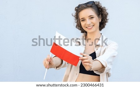 Portrait of a young female student in her hands holding the flag of Poland. Royalty-Free Stock Photo #2300466431