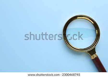 Magnifying glass on light blue background, top view. Space for text