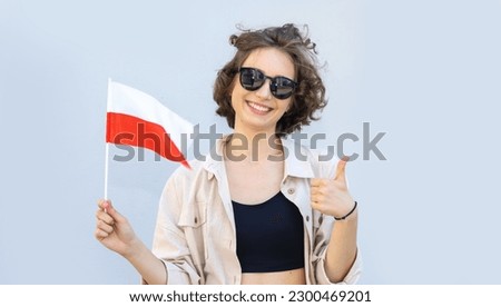 Beautiful woman in sunglasses holds the flag of Poland in her hands and shows a thumbs up. Royalty-Free Stock Photo #2300469201