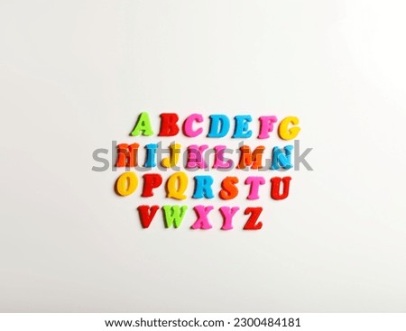 Colorful magnetic letters on white background, flat lay. Alphabetical order