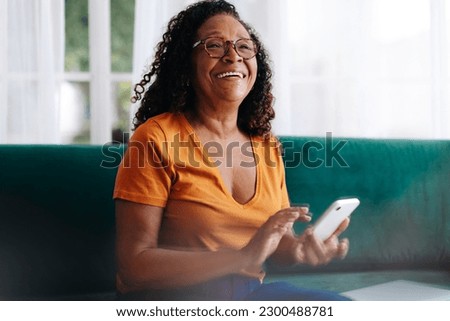 Retired woman using her smartphone to stay connected with her loved ones. Senior woman using mobile technology to make phone calls, send text messages, access social media, and browse the internet. Royalty-Free Stock Photo #2300488781