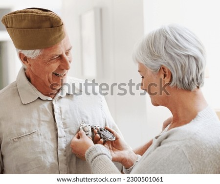 Military veteran, man and woman with medal, uniform and smile together with memory, pride and success. Elderly couple, army badge or regalia with happiness, check and retirement from service in house Royalty-Free Stock Photo #2300501061