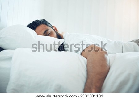 Tired, relax and a man on a bed for sleep, depression and fatigue at home. Rest, napping and a guy sleeping in the bedroom with insomnia, narcolepsy or depressed while lying looking exhausted Royalty-Free Stock Photo #2300501131
