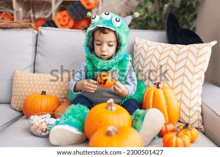 Adorable hispanic boy having halloween party holding pumpkin basket at home